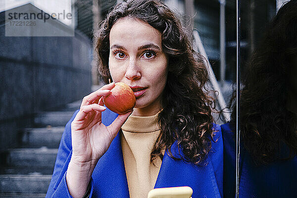 Schöne weibliche Fachkraft isst frischen Apfel
