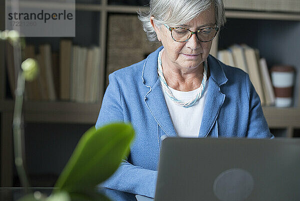 Konzentrierte Geschäftsfrau bei der Arbeit am Laptop im Heimbüro