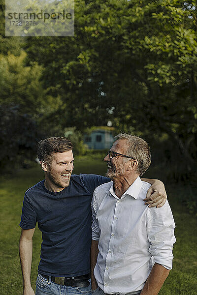 Lachender Sohn  der seinen Vater umarmt  während er im Hinterhof steht