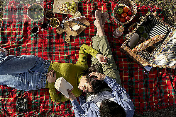 Frau entspannt sich auf dem Schoß ihres Freundes auf einer Decke beim Picknick