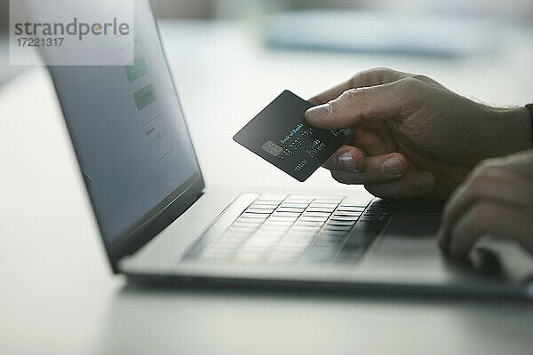 Mann  der eine Online-Zahlung per Kreditkarte auf einem Laptop vornimmt