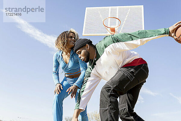 Glücklicher Mann und Frau spielen Basketball auf dem Platz