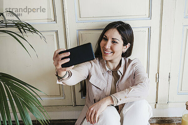 Schöne Frau nimmt Selfie beim Sitzen zu Hause