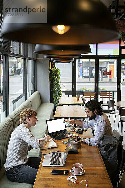 Männliche Unternehmer diskutieren am Laptop im Coworking-Büro