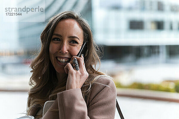 Lächelnde blondhaarige Geschäftsfrau  die mit einem Mobiltelefon spricht