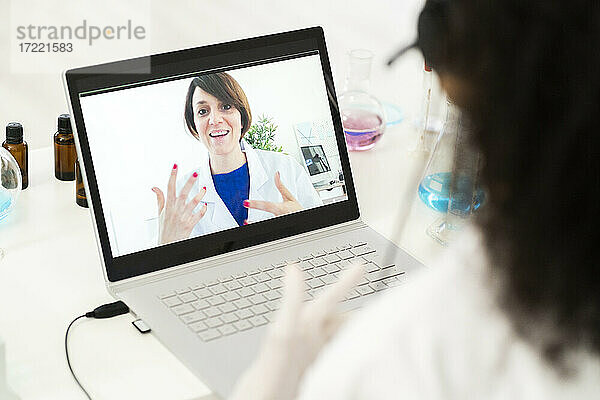 Eine Ärztin diskutiert per Videoanruf über einen Laptop im Labor