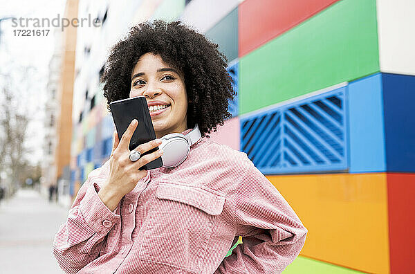 Junge Frau lächelt  während sie mit einem Mobiltelefon spricht