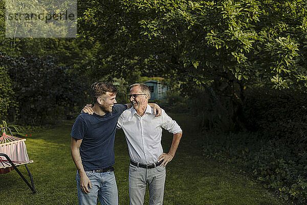 Lachender Sohn und Vater mit Arm um stehen im Hinterhof
