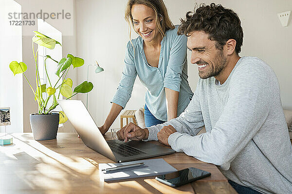 Fröhliches Paar bei der Arbeit am Laptop im Home Office