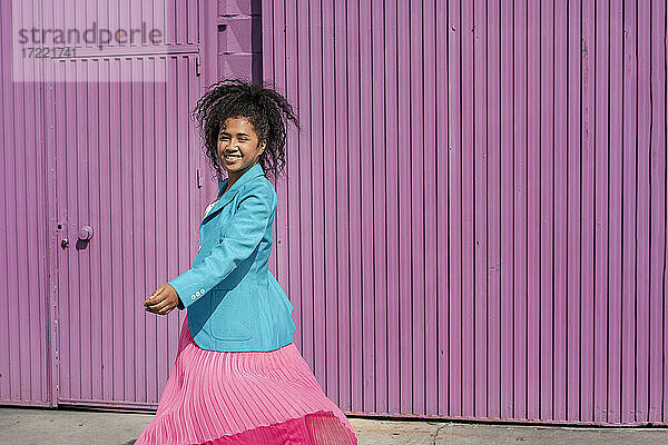 Lächelnde Frau mit Afrofrisur vor lila Kabine