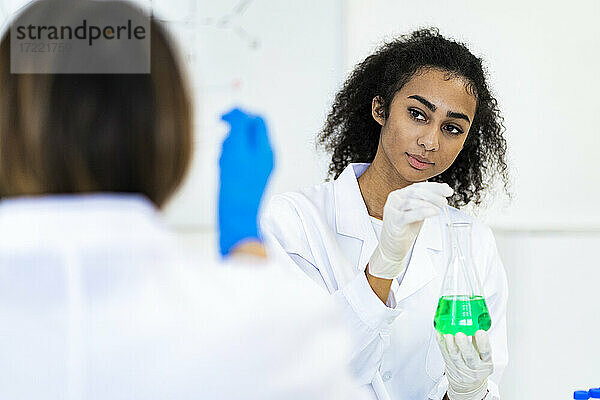 Weibliche Forscherin  die einen Mitarbeiter bei der Arbeit im Labor ansieht