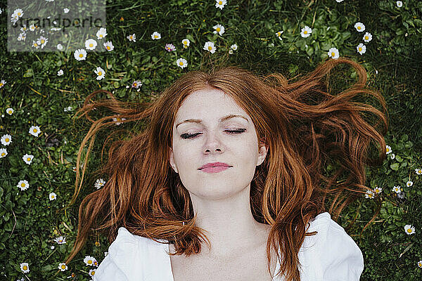 Junge rothaarige Frau im Gras liegend