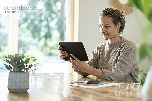 Geschäftsfrau  die ein Tablet benutzt  während sie am Tisch sitzt