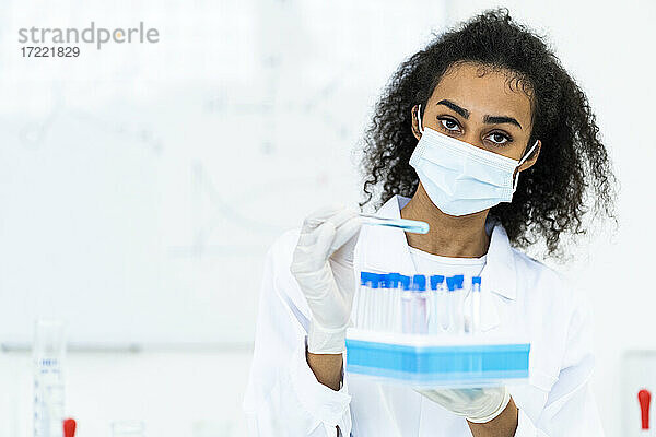 Eine Forscherin hält eine Mikroplatte im Labor während einer Pandemie