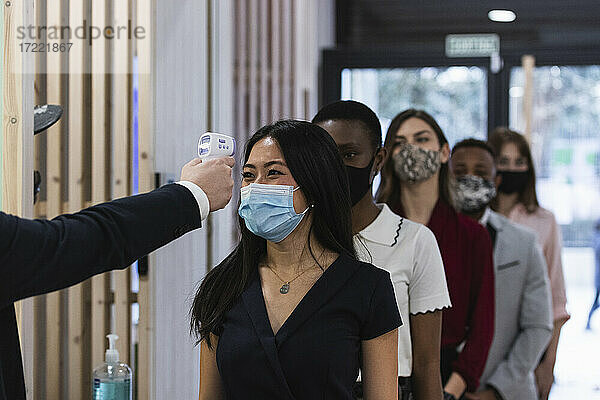 Mitarbeiter mit Gesichtsmaske beim Durchlaufen der Temperaturkontrolle im Büro