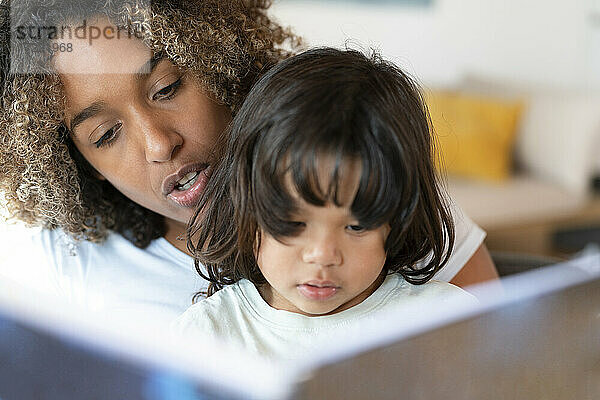 Mutter liest ihrer Tochter zu Hause ein Buch vor