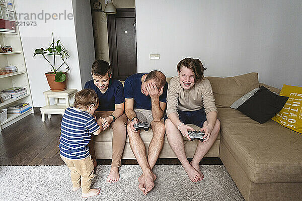 Vater mit Söhnen beim Spiel zu Hause