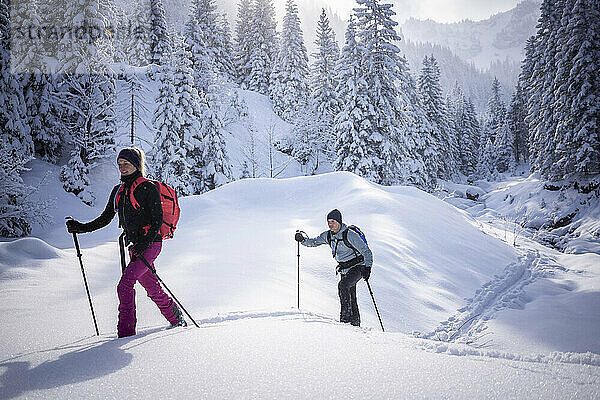 Mittlere erwachsene Frau beim Skitourengehen mit Mann an einem sonnigen Tag