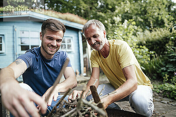 Sohn und Vater arrangieren Feuerholz  während sie im Hinterhof kauern