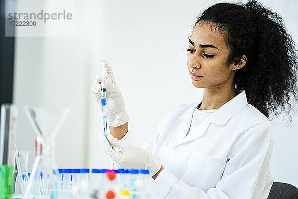 Junge Forscherin beim Einspritzen einer Flüssigkeit in ein Reagenzglas im Labor