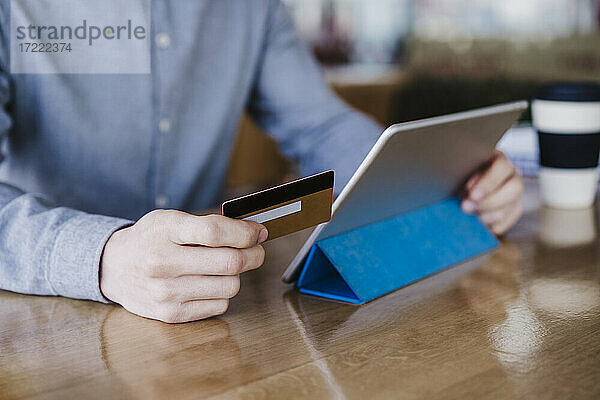 Geschäftsmann hält digitale Tablette und Kreditkarte über Schreibtisch im Büro