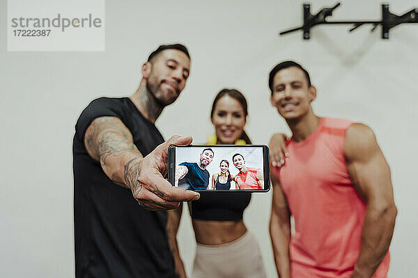 Mittlerer Erwachsener  der ein Selfie mit seinem Handy im Fitnessstudio macht