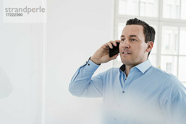 Geschäftsmann schaut beim Telefonieren am Arbeitsplatz weg