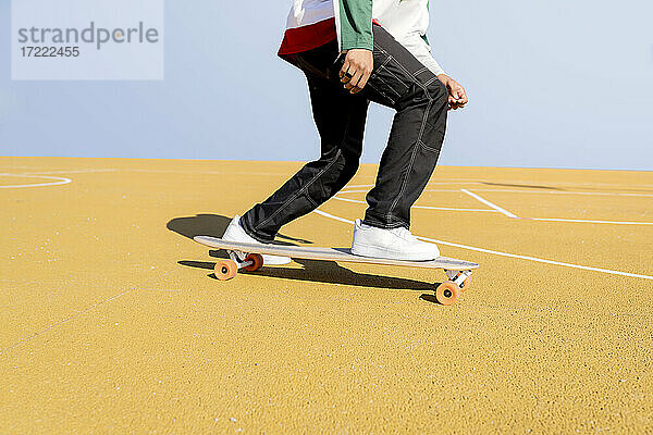 Junger Mann fährt Skateboard auf einem Sportplatz