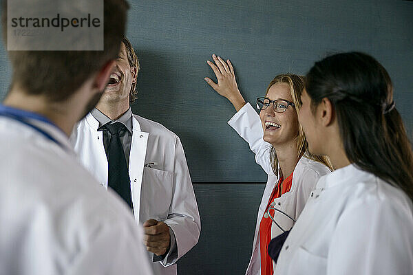 Fröhliches männliches und weibliches Gesundheitspersonal bei einer Diskussion im Krankenhaus