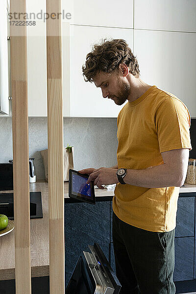 Mann benutzt digitales Tablet in der Küche zu Hause