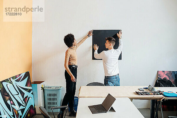 Junges Paar klebt Karton an die Wand im Atelier
