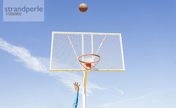 Sportlerin spielt Basketball unter dem Himmel