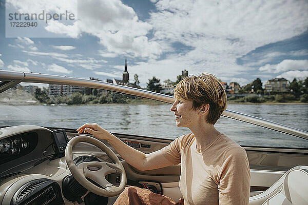 Lächelnde Frau  die ein Motorboot fährt und dabei wegschaut