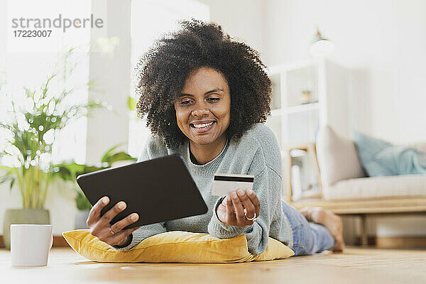 Junge lächelnde Frau mit digitalem Tablet und Kreditkarte zu Hause