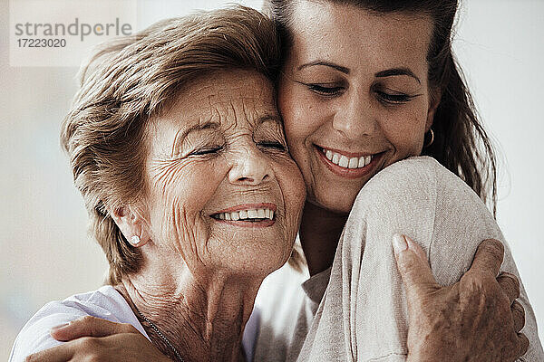 Glückliche junge Frau und Großmutter  die sich zu Hause umarmen