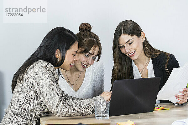 Lächelnde Unternehmerinnen arbeiten am Laptop im Büro