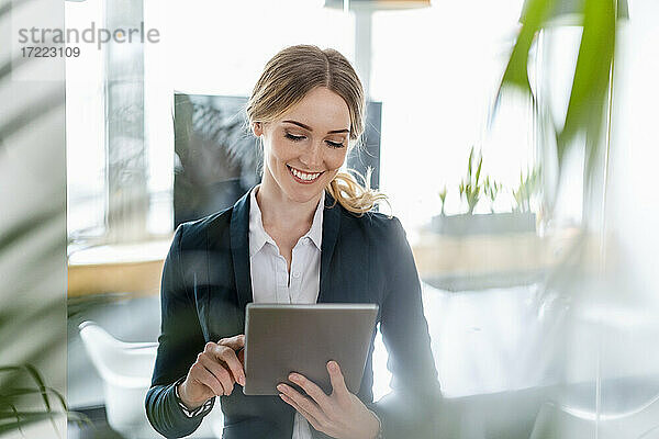 Zufriedene Geschäftsfrau bei der Arbeit am digitalen Tablet im Büro