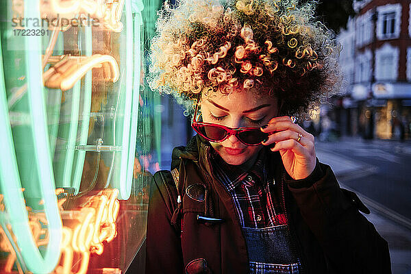 Frau mit Sonnenbrille vor beleuchteten Neonröhren