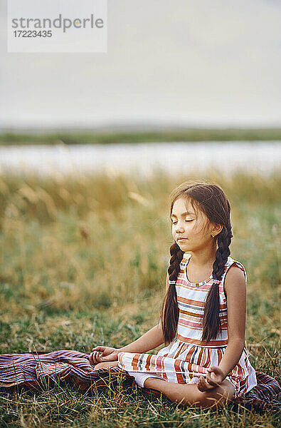 Niedliches Mädchen meditiert im Gras