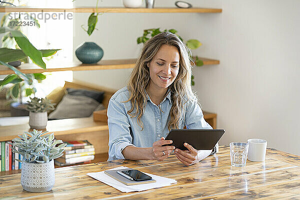 Lächelnde Geschäftsfrau  die am Tisch sitzend ein Video ansieht