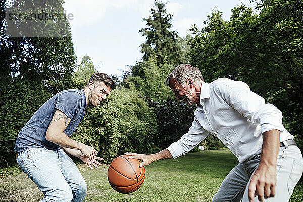 Vater spielt Basketball mit Sohn im Hinterhof an einem sonnigen Tag