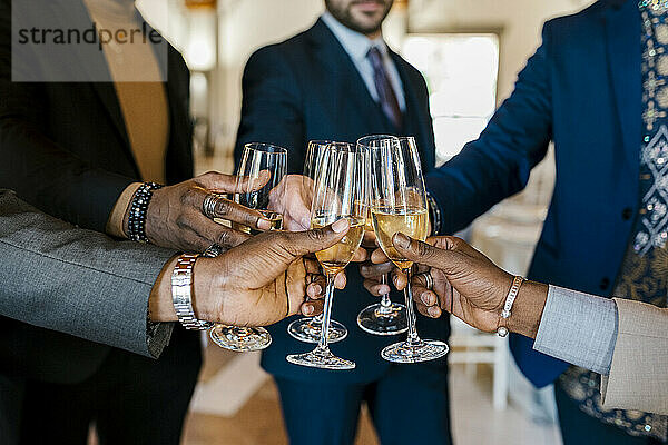 Hände von eleganten Männern  die bei einem Bankett mit Champagner anstoßen