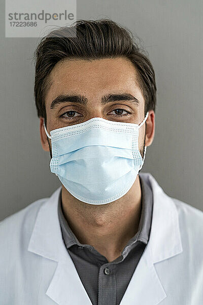 Männlicher Mitarbeiter des Gesundheitswesens trägt bei COVID-19 eine Schutzmaske