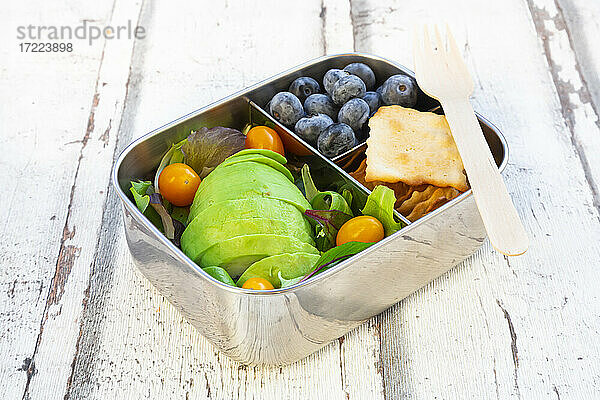 Lunchbox mit Salat  Avocado und gelben Tomaten  Crackern und Heidelbeeren