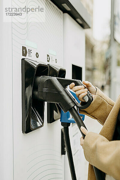 Frau an einer Ladestation für Elektrofahrzeuge in der Stadt