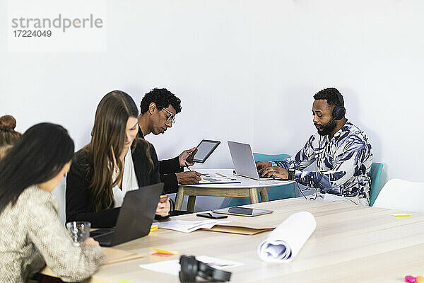 Geschäftsleute bei der Arbeit  während sie mit Kollegen in einem kreativen Büro sitzen
