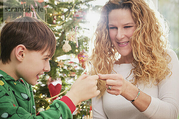 Glückliche Mutter und Sohn halten einen Wunschknochen mit einem Weihnachtsbaum im Hintergrund