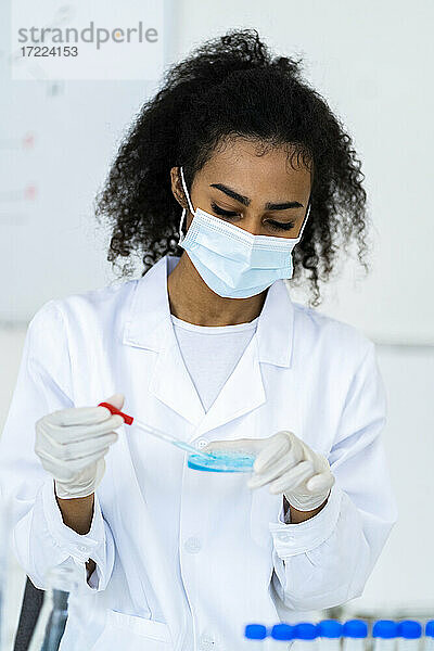 Junge Forscherin testet Flüssigkeit im Chemielabor während COVID-19