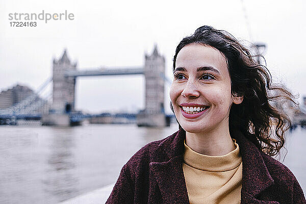 Lächelnde junge Frau  die wegschaut  mit der Tower Bridge im Hintergrund