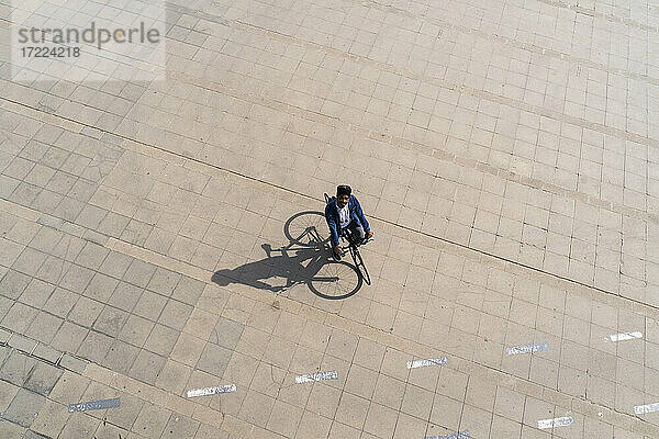Mann fährt mit dem Fahrrad auf der Promenade und blickt an einem sonnigen Tag nach oben